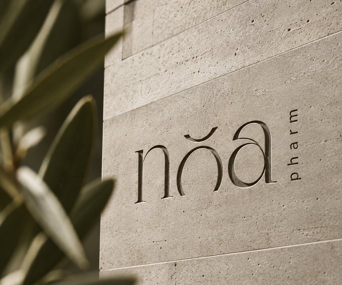 Logotip Noa Pharm uklesan u kamenu, uz grane masline
